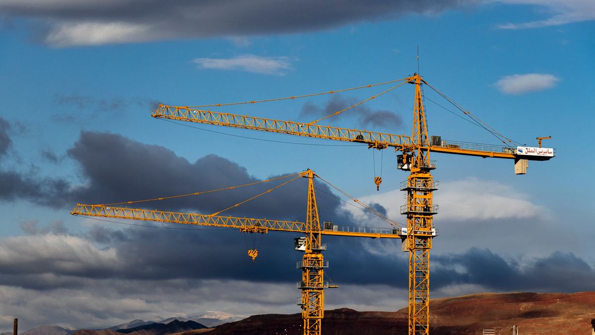 Tower cranes standing against the sky above a construction site