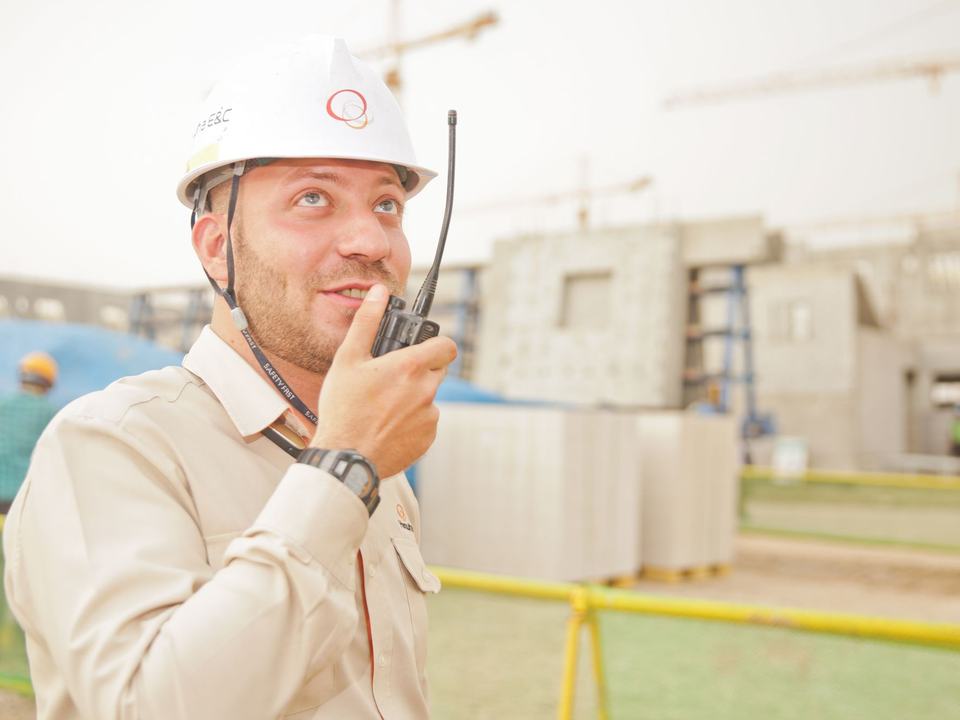 Site inspector with a two-way radio checking equipment on a yard