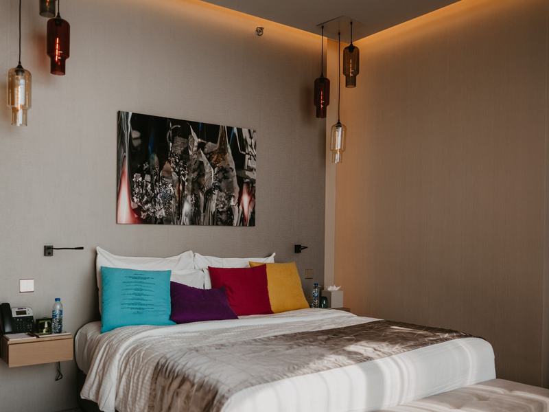 Hotel guest room with bed, headboard, side tables and lighting